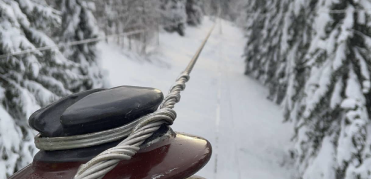Foto av høyspent isolator i vinterlandskap med skogbakgrunn