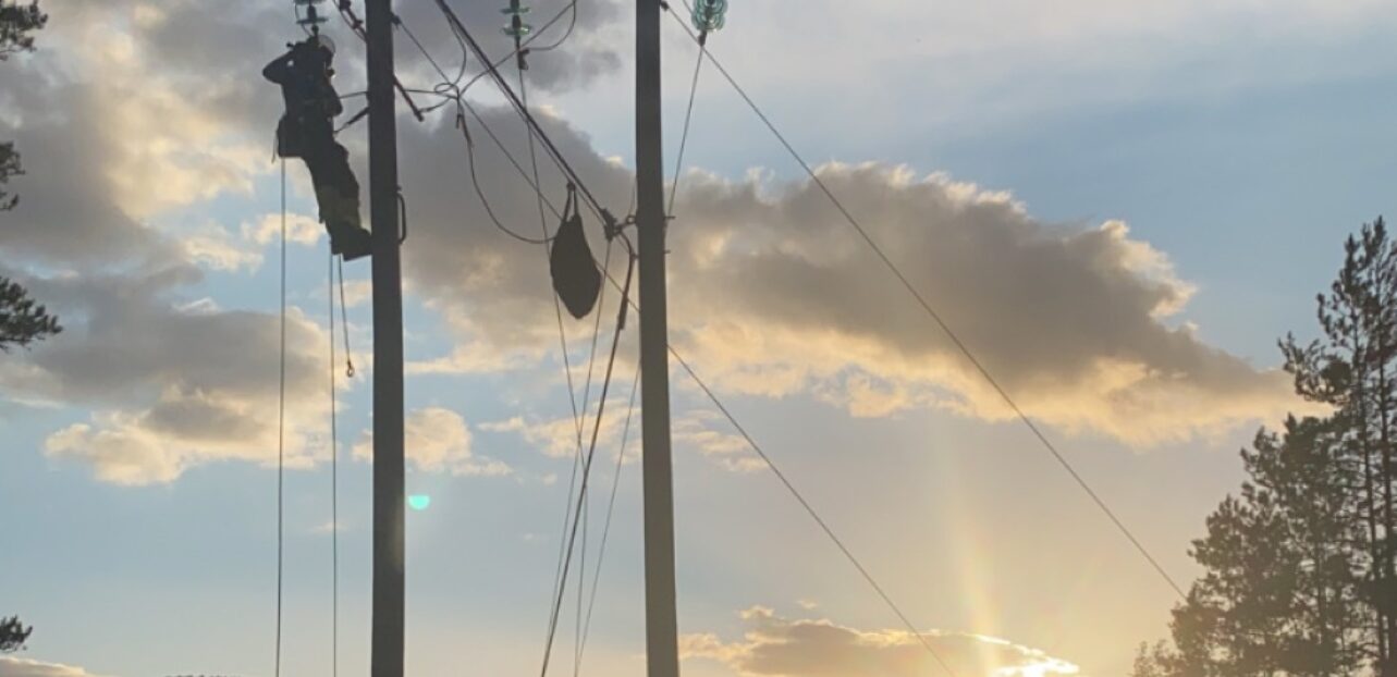 Bilde av montør i høyspentmast i solnedgang